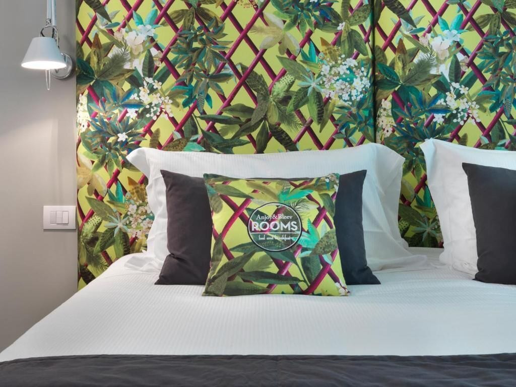 Ein Hotelzimmer mit einem Bett, einem dekorativen, mit einem Blumenmuster versehenen Kopfteil und einer Wandleuchte.