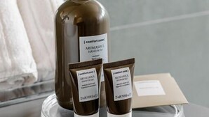 Ein Badezimmer mit einer großen Handseifenflasche und zwei kleinen Handcremetuben auf einer klaren Ablagefläche.