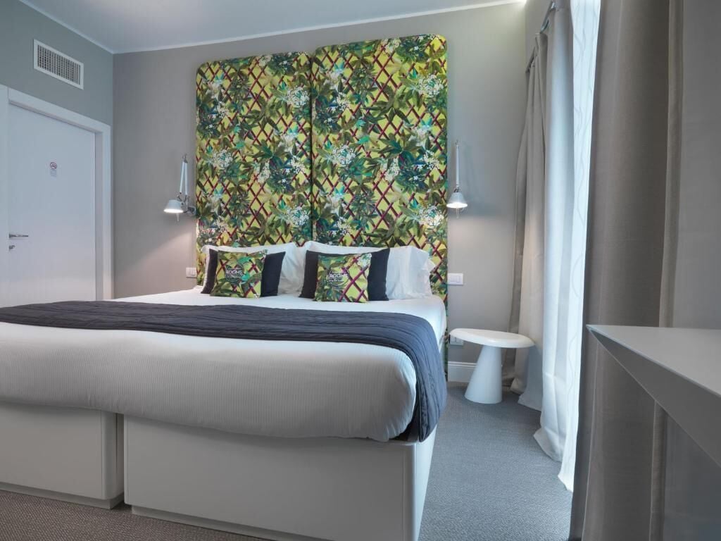 A modern bedroom with a large bed, a bedside table, and a headboard with a colorful pattern.