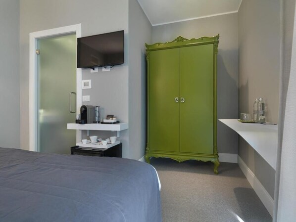 A bedroom with a bed, a green wardrobe, a television mounted on the wall, and a small shelf with toiletries. - Anjoy&Bleev Rooms (Rho)