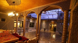 A traditional interior with ornate arches, a chandelier, and a dining area with a red tablecloth. - "S E A S O N S"  (Samarkand)
