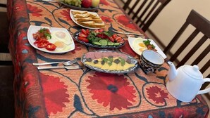 Een eettafel met een tafelkleed met bloemenprint, diverse serviezen en een theepot.