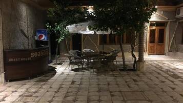 A guest house with a tiled floor, outdoor seating area, and a Pepsi sign.