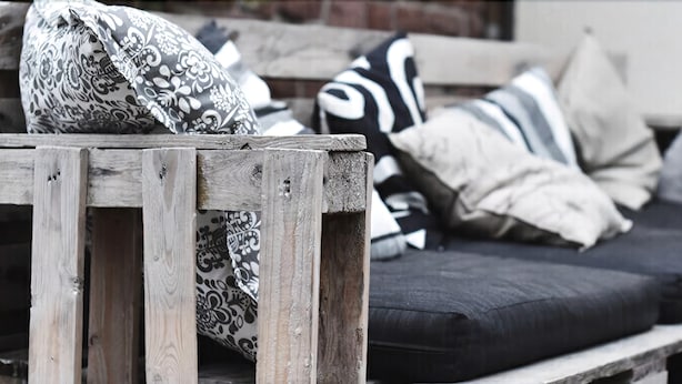 A wooden bench with a patterned cushion and a black sofa with striped pillows. - Quartier restaurant Zum Hannes (Winterbach)