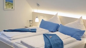 A neatly made bed with white linens and blue accents, a bedside lamp, and a framed picture on the wall. - Quartier restaurant Zum Hannes (Winterbach)