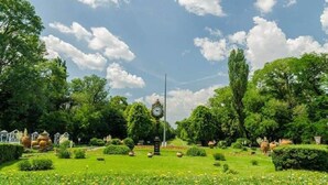 A well-maintained garden with a central clock tower, surrounded by lush greenery and various garden features.