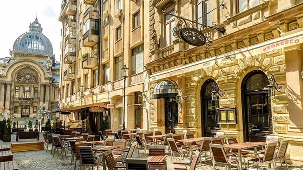 An outdoor café with tables and chairs, a building with 'NEGRESCO' signage, and a domed structure in the background.