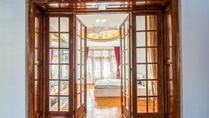 A wooden door leading to a bedroom with a bed, a ceiling fan, and a view of the outside.
