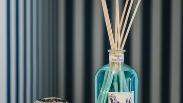Una botella azul con ramitas, dos objetos esféricos metálicos y un fondo a rayas.