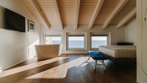 A bedroom with a large window, a bathtub, and a bed. - Numa Hotel (Numana)