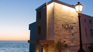 A building with the name "NUMA" on its facade, a street lamp, and a view of the sea. - Numa Hotel (Numana)