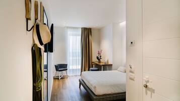 A hotel room with a bed, a desk, a chair, and a wardrobe.