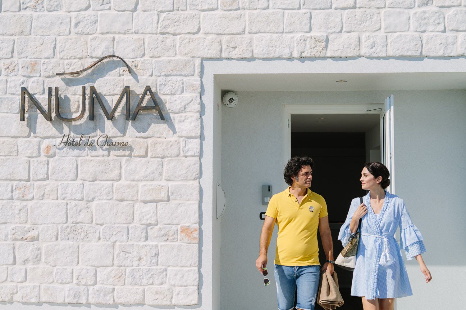 Entrada de hotel con fachada de ladrillo blanco y un letrero que dice "NUMA Hotel de Chambre".