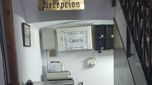 A reception area with a sign reading "Reception" and a sign above a counter that says "Cazorra". - Hotel Andalucia (Cazorla)