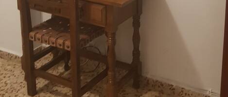 Un escritorio de madera con una computadora y una silla, un espejo en la pared y un piso con manchas.