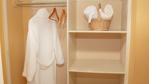 Un baño con una bañera blanca, una toalla blanca colgada en un perchero y una cesta de mimbre en un estante.