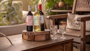 Tres botellas de vino sobre una mesa de madera con dos copas.