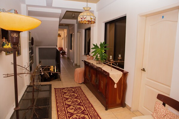 A hallway with a wooden bench, a patterned rug, a hanging lamp, and a door marked with the number 9.