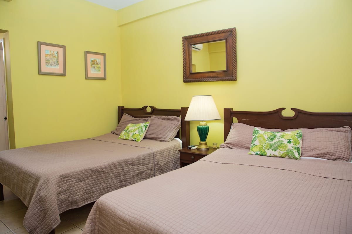 Una habitación de hotel con dos camas, una lámpara de noche y un espejo en la pared.
