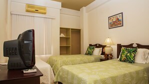Habitación de hotel con dos camas, televisión, escritorio y armario.