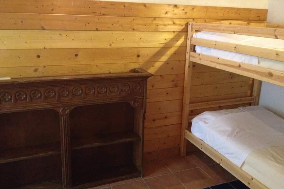 A bunk bed room with wooden walls and a lower shelf.