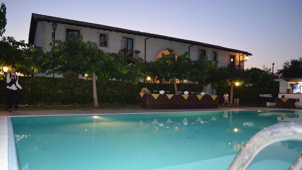 A swimming pool with a clear view of the poolside area, a building with a tiled roof, and a well-lit outdoor space. - Aranceto Turismo Rurale (Syracuse)