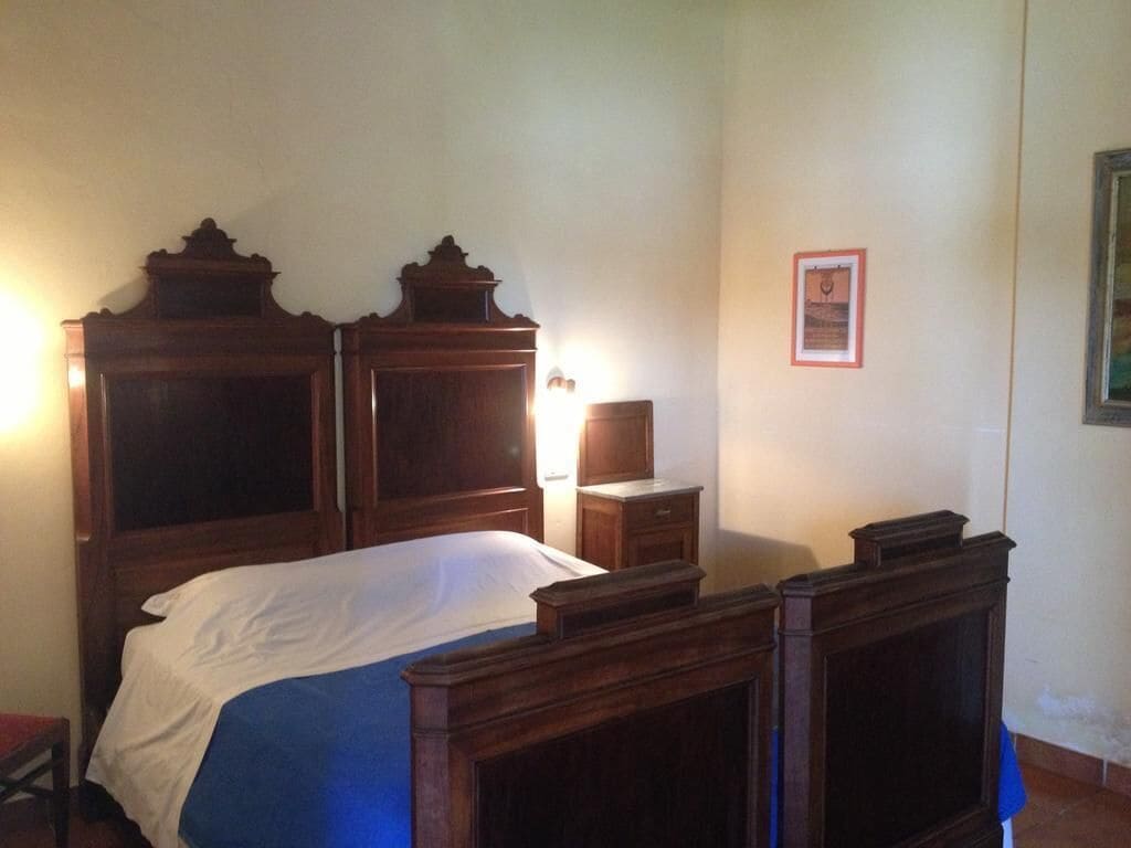 A bedroom with a large wooden bed, a nightstand, and a framed picture on the wall.