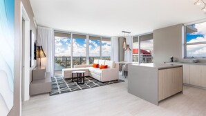 Un apartament modern amb un balcó gran, un sofà, zona de menjador i cuina.