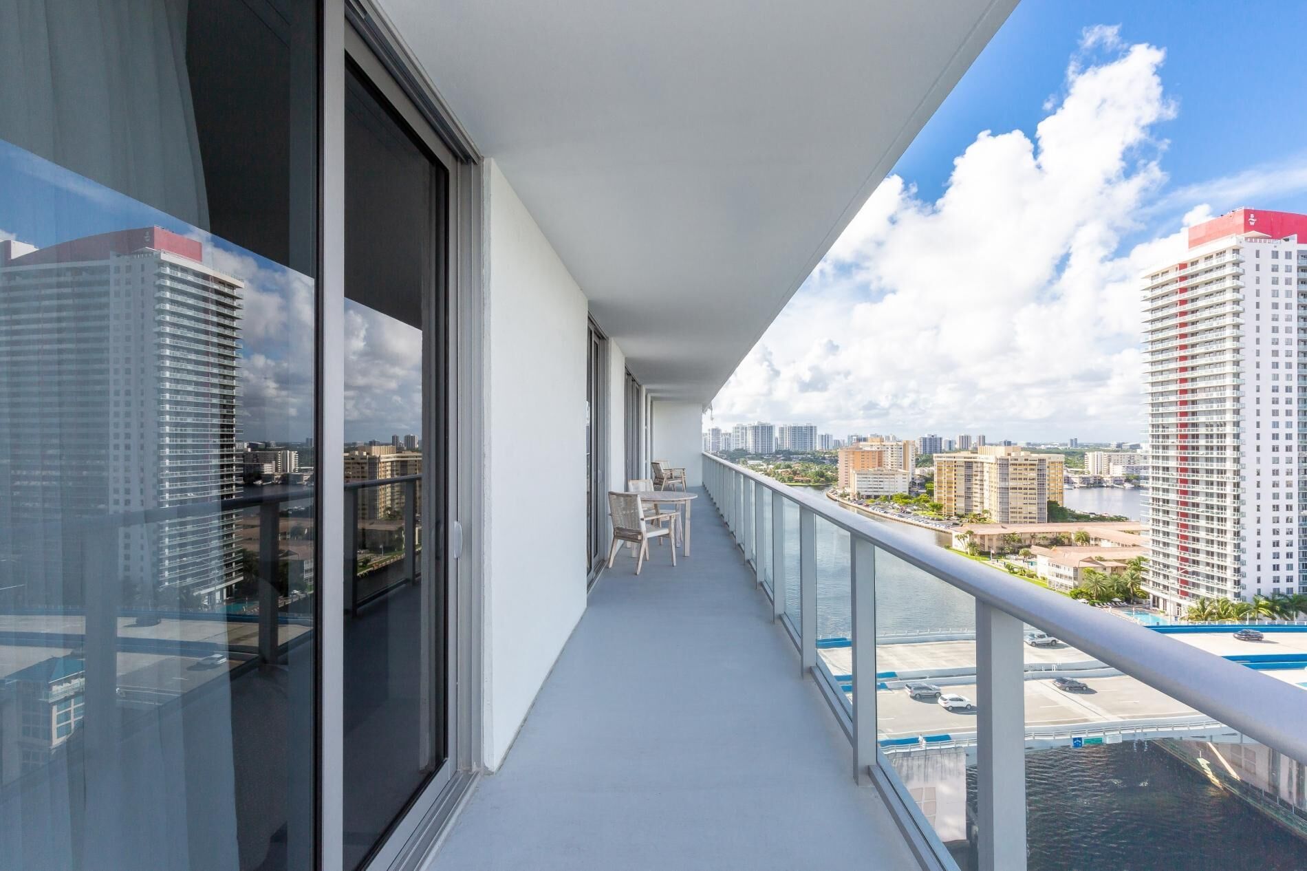 A balcony with a view of a cityscape, including high-rise buildings and a body of water.