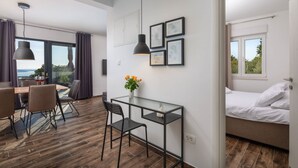 Een moderne hotelkamer met een bed, een klein bureau en een zithoek met stoelen en een tafel.