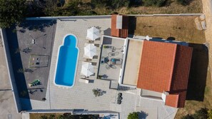 Vista aérea de una propiedad con piscina, zona de estar exterior y un porche cubierto.
