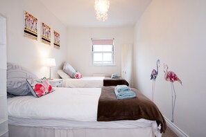 A bedroom with two beds, a window, and wall art. - Dalton Crescent (Durham)