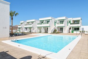 Un hotel moderno con piscina, varios balcones y vista despejada a las montañas.