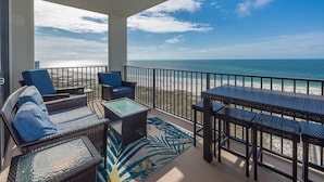 A balcony with wicker furniture, a glass-top table, and a patterned rug. - 3BR Relax on the Gulffront balcony! Phoenix VI 61408 (Orange Beach)