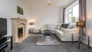 A modern living room with a fireplace, a sofa, a coffee table, and a TV. - Broome Road (Durham)