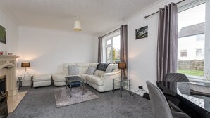 A living room with a white sofa, a coffee table, a fireplace, and a dining area with a table and chairs. - Broome Road (Durham)