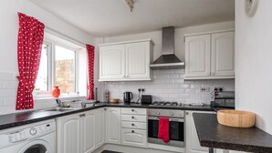 A modern kitchen with white cabinets, a washing machine, a stove, and a sink. - Broome Road (Durham)