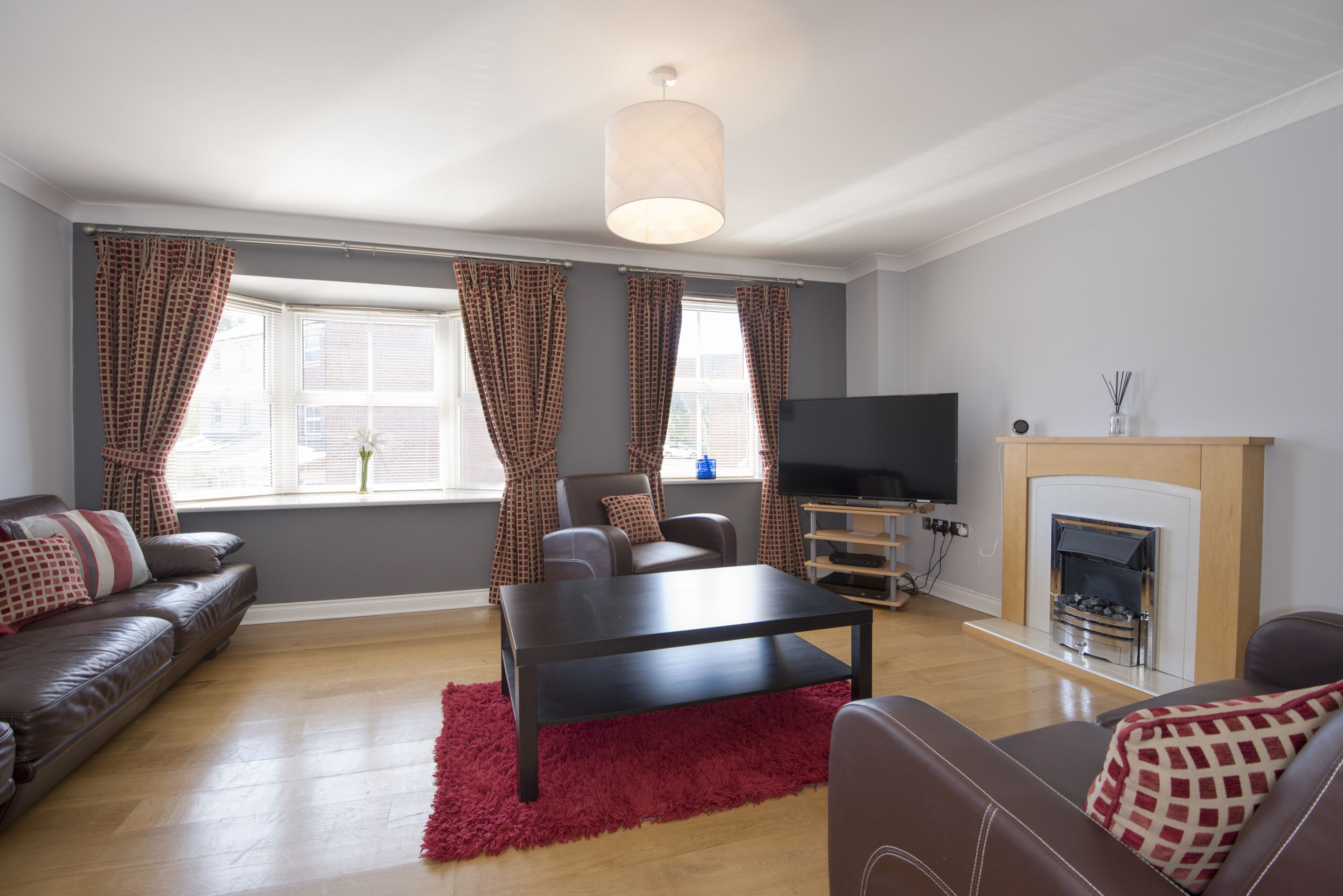 A living room with a sofa, a coffee table, a TV, and a fireplace.
