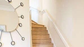 A wooden staircase with white railings and a wall-mounted circular light fixture. - Hillbrook (Stockton-on-Tees)