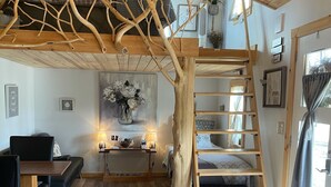 A cozy room with a wooden ceiling, a loft bed, a dining area, and a staircase. - Cedar Twig Cabin: Serene and cozy (Mt. Juliet)