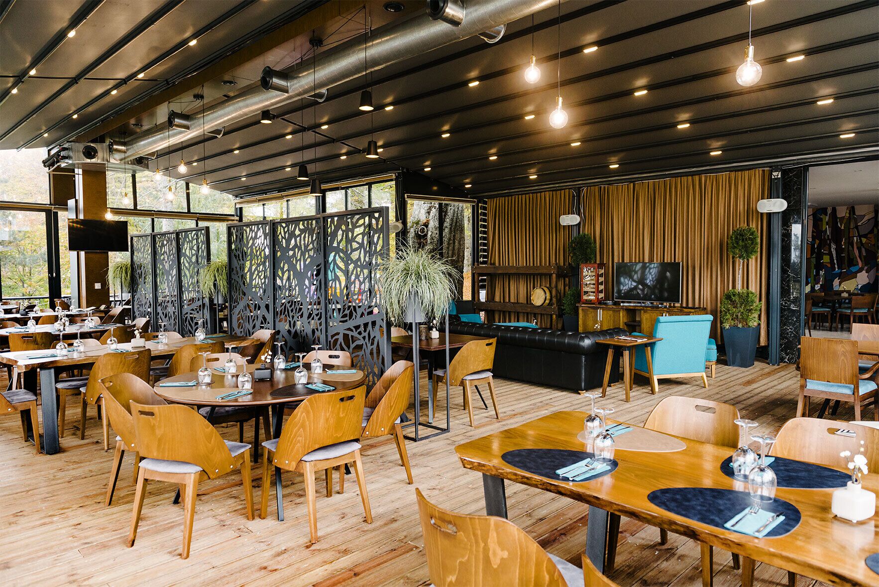 A restaurant with wooden tables and chairs, a bar area, and a television screen.