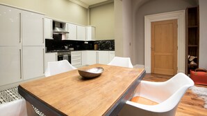 Eine moderne Küche mit weißen Schränken, einem Holztisch und weißen Stühlen.