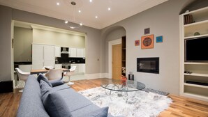 Ein modernes Wohnzimmer mit einem grauen Sofa, einem Glastisch und einem weißen, flauschigen Teppich.