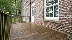 A brick building with a wooden deck and a large window. - Apartment 2 The Grove (Durham)