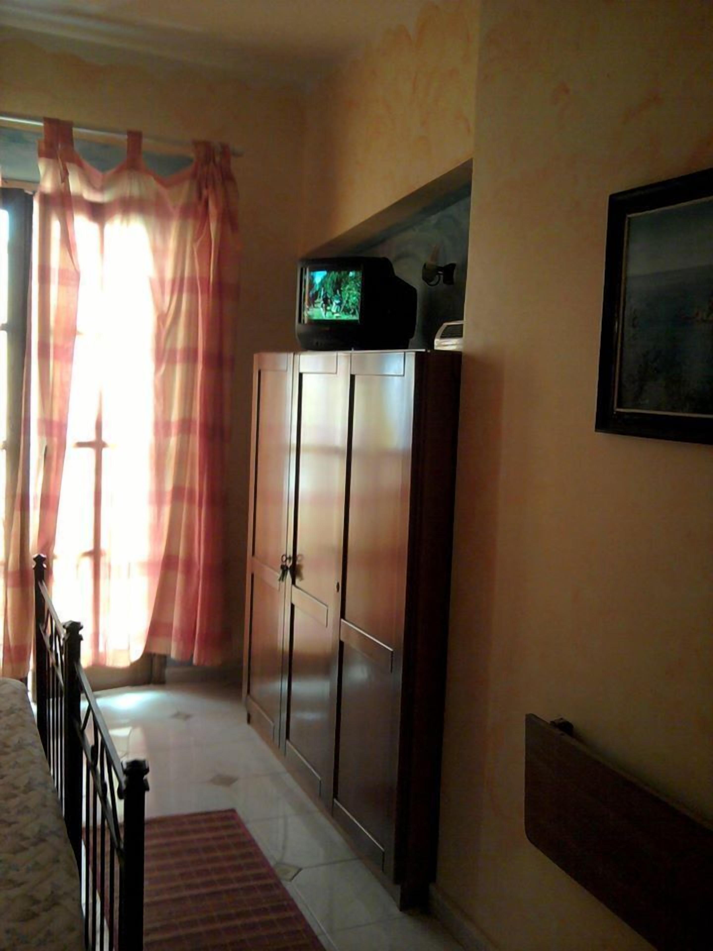 Un pasillo con un armario, un televisor encima y un cuadro en la pared.