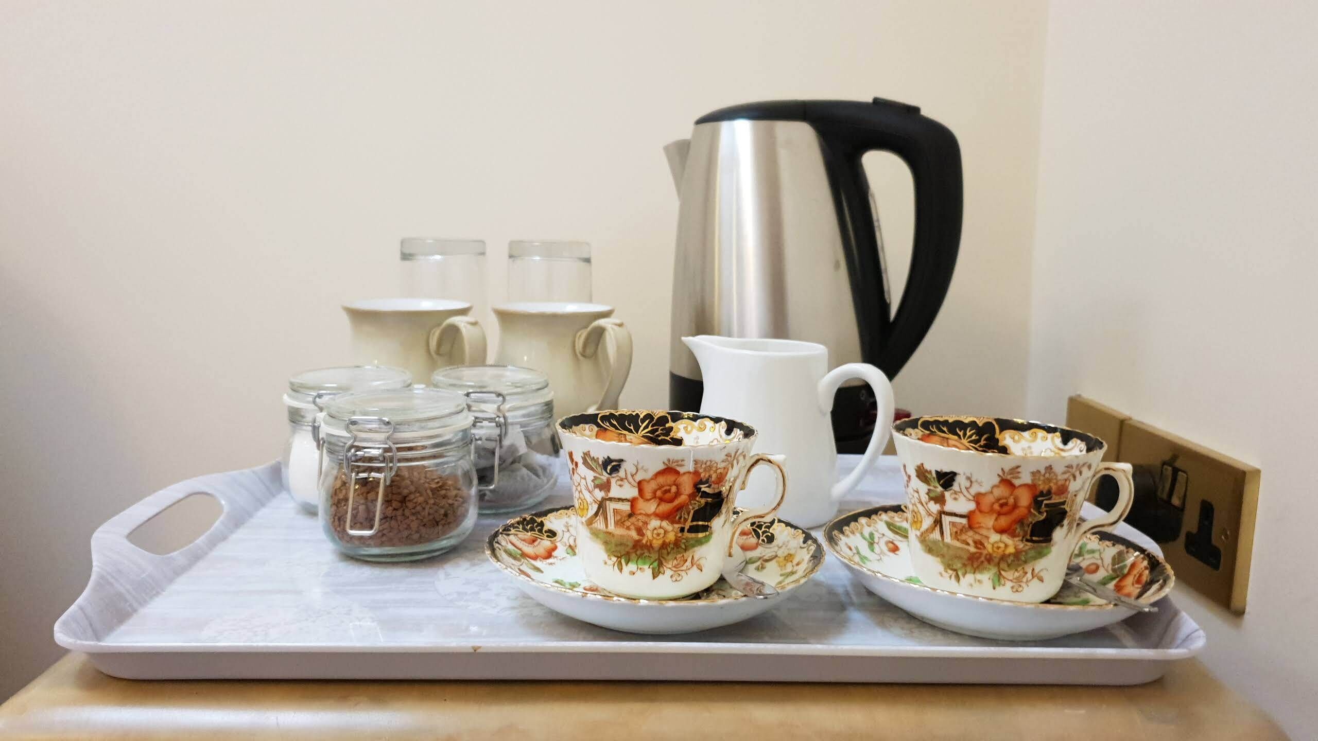A tray with a coffee maker, two cups, and two sugar containers.