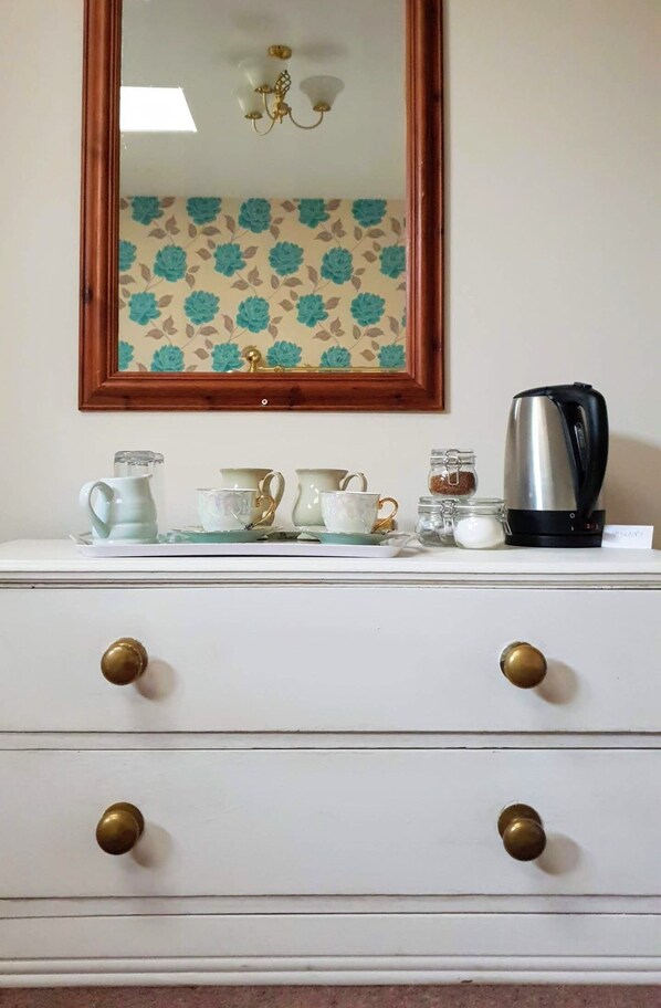 A white dresser with brass knobs, a mirror above it, and a floral-patterned wallpaper. - Station House (South Brent)