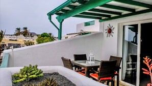 A balcony with a table and chairs, a decorative lantern, and a view of the cityscape.
