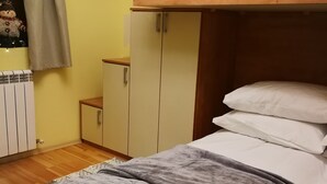 A bunk bed with a grey blanket, a wooden headboard, and a white pillow.