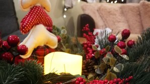 A Christmas decoration with a candle, pine branches, and red berries.